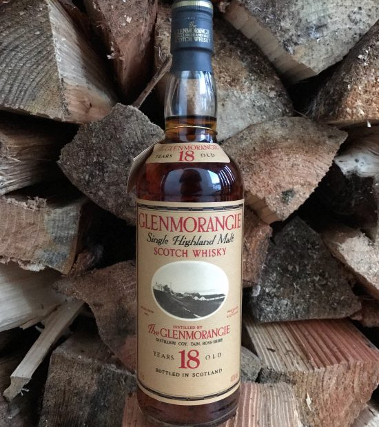 18 Year Old Glenmorangie Bottle on display in front of a wall of firewood.